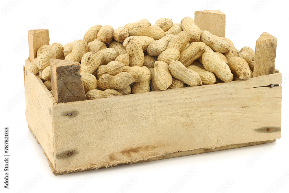 bunch of roasted peanuts in a wooden box on a white background