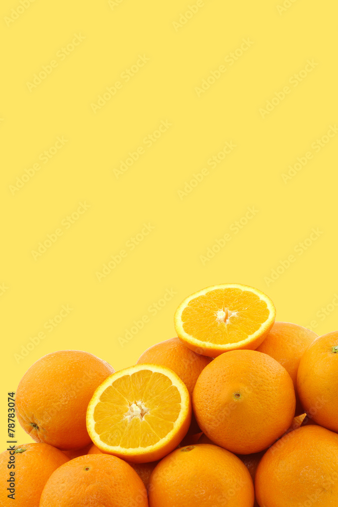 Fotografie fresh oranges and two halves on a yellow background