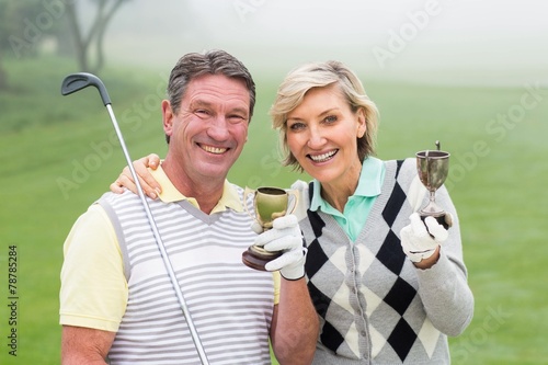 Happy golfing couple with trophy photo