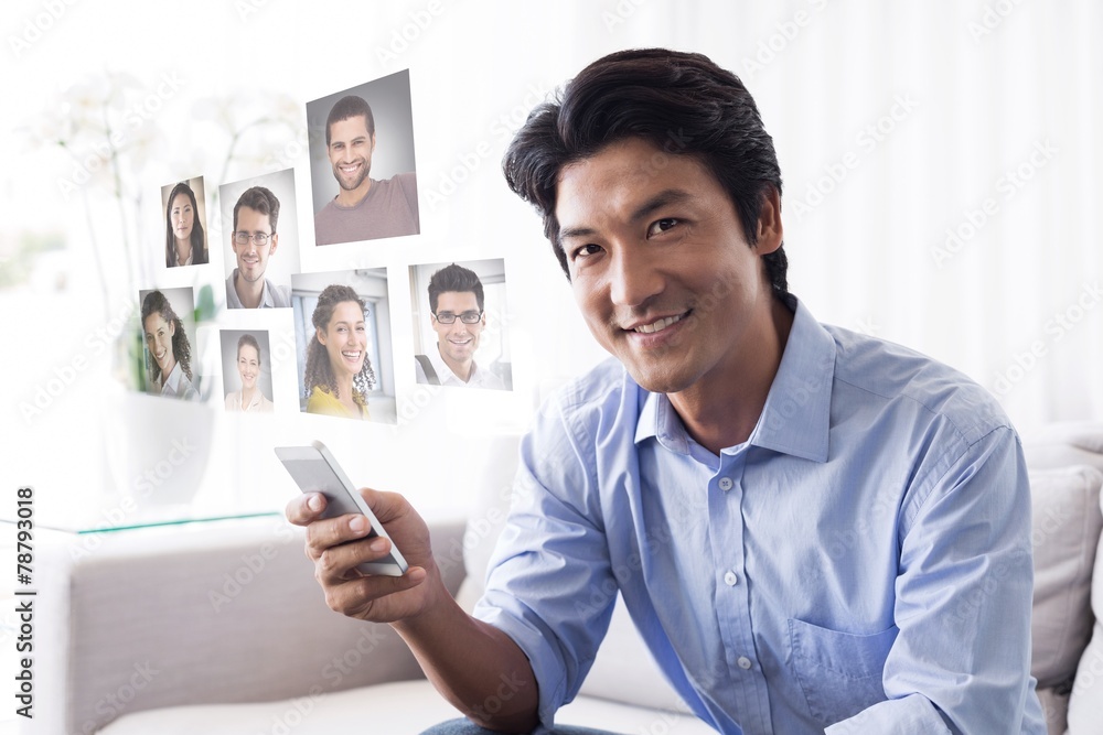 Composite image of happy man sitting on couch texting on phone Composite image of happy man sitting on couch texting on phone