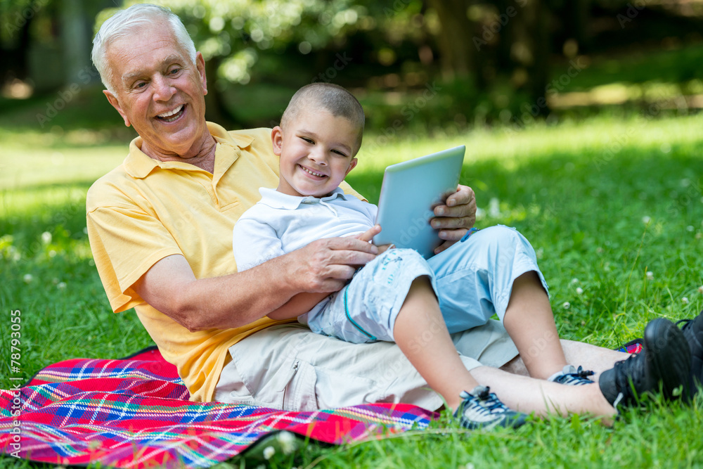 Fototapeta premium grandfather and child in park using tablet