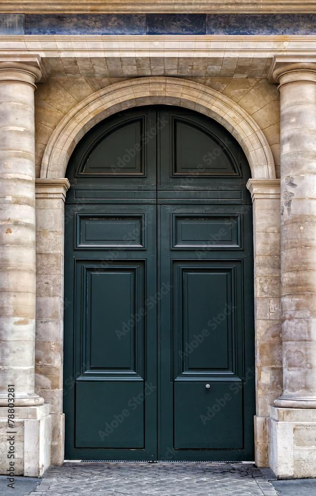 Old wooden front door painted black in Paris