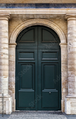 Old wooden front door painted black in Paris