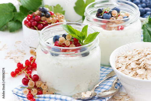 yogurt with fresh berries and breakfast foods on table