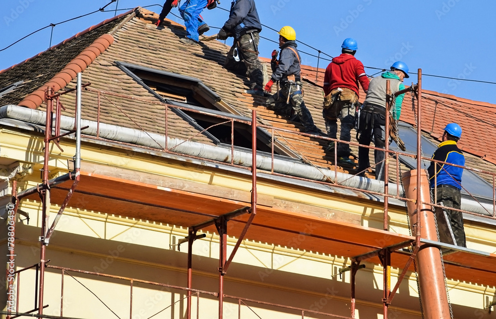 Roofers are working on the roof of an old building