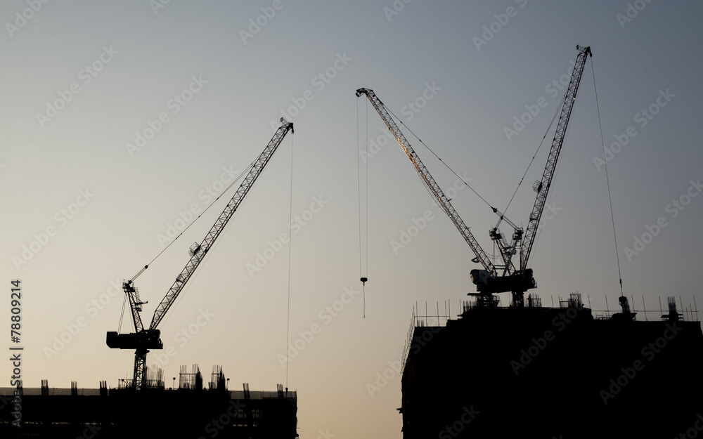 Silhouette of under construction building and cranes
