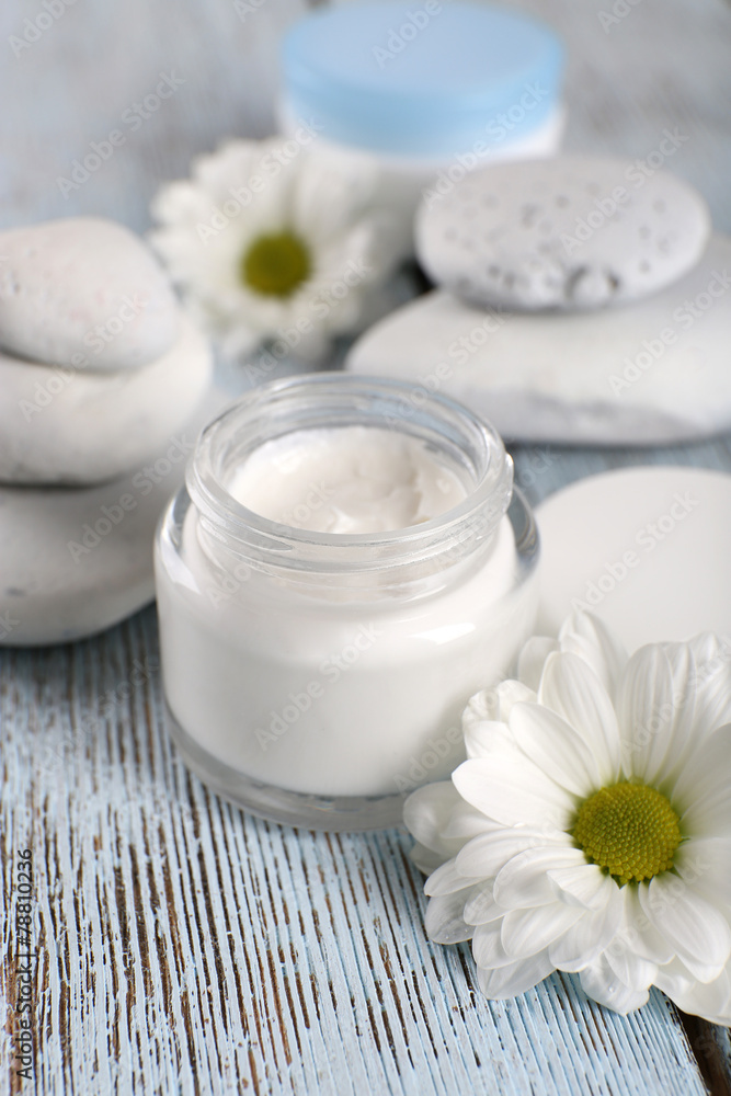 Cosmetic cream with flowers and spa stones on wooden background Cosmetic cream with flowers and spa stones on wooden background