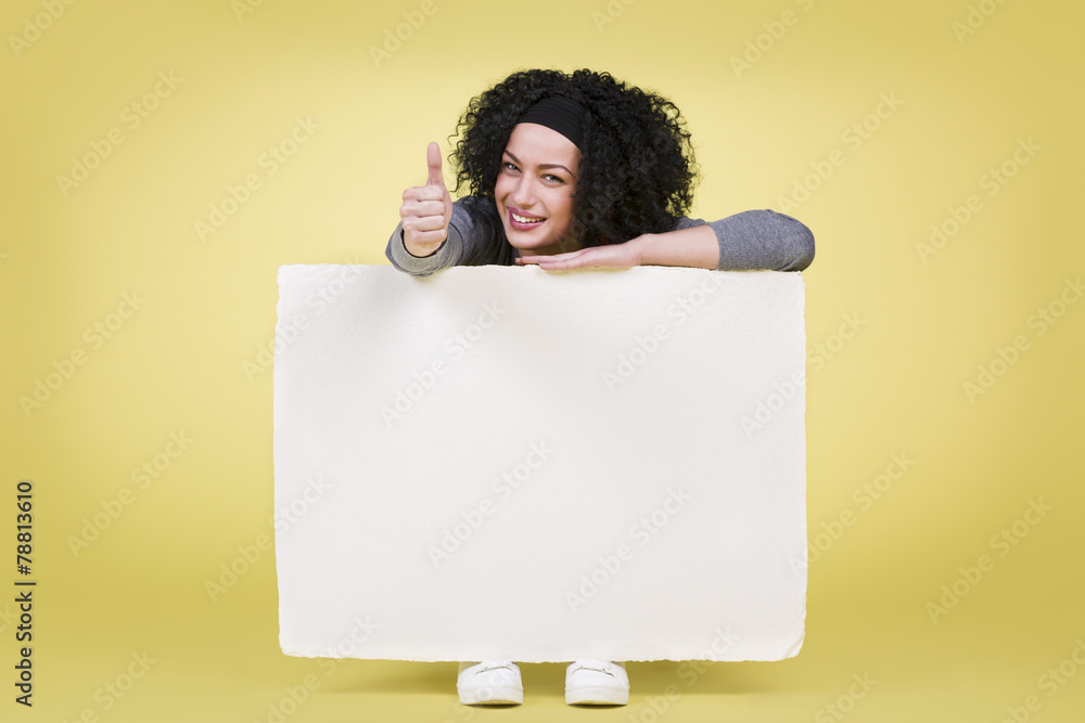 Smiling woman holding a white sign board showing thumbs up Smiling woman holding a white sign board showing thumbs up
