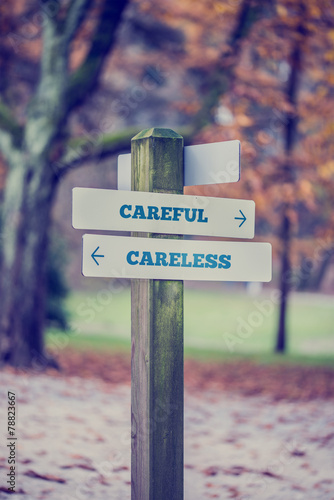 Rustic wooden sign in an autumn park with the words Careful - Ca
