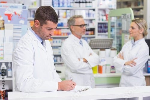 Pharmacist in lab coat writing a prescription