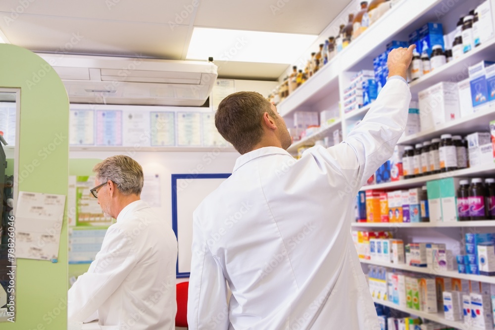 Pharmacist in lab coat taking jar from shelf