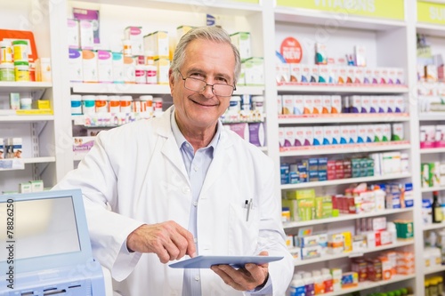 Smiling pharmacist using tablet pc photo