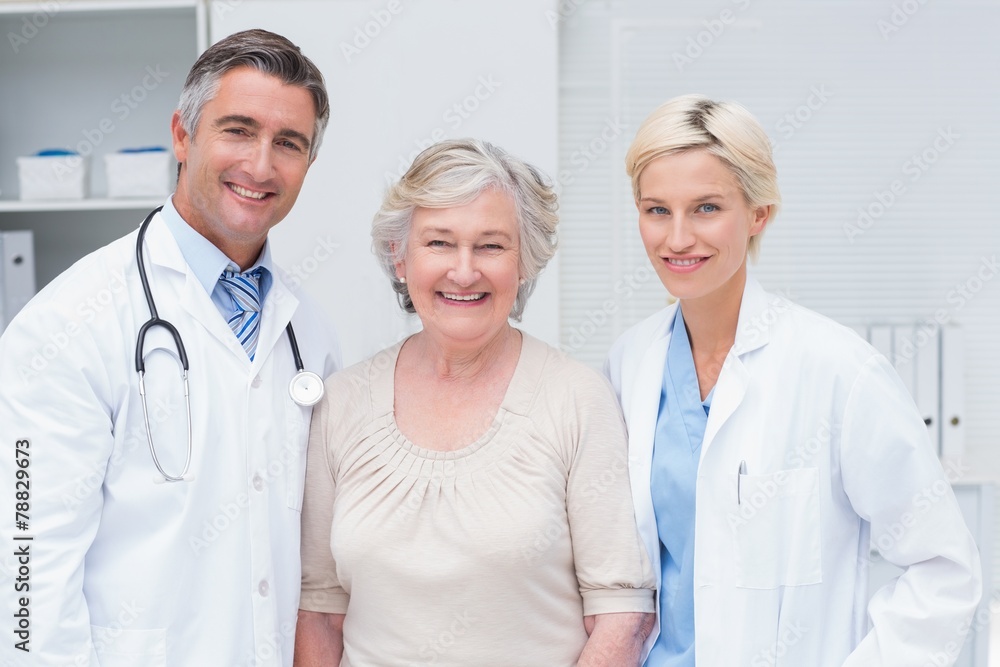 Doctors and senior patient smiling in clinic Doctors and senior patient smiling in clinic