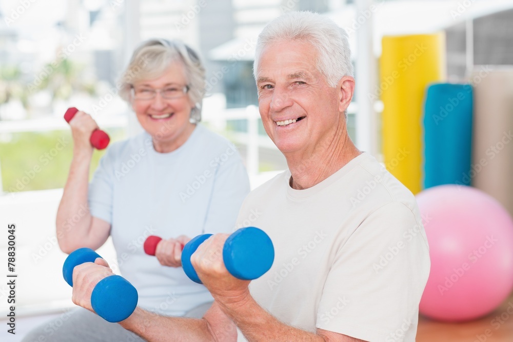 Happy senior couple lifting dumbbells in gym Happy senior couple lifting dumbbells in gym