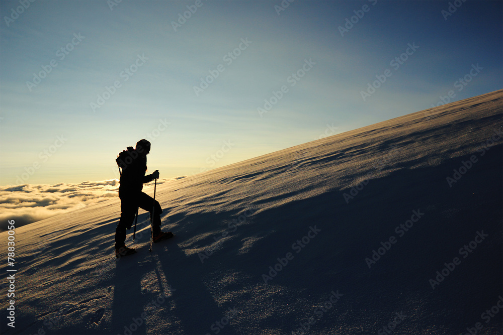 girl goes on a snowy slope in the mountains against sun