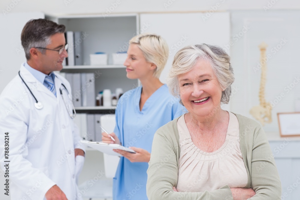 Patient smiling while doctor and nurse discussing in background Patient smiling while doctor and nurse discussing in background