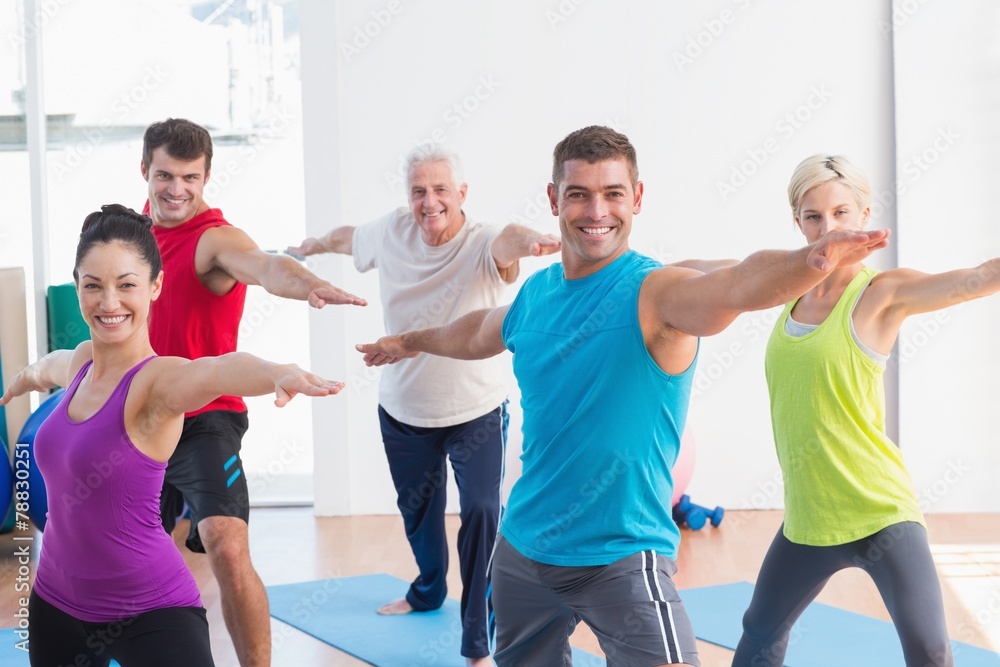 People doing warrior pose in yoga class - obrazy, fototapety, plakaty 