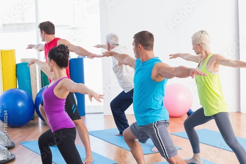 People doing warrior pose in yoga class