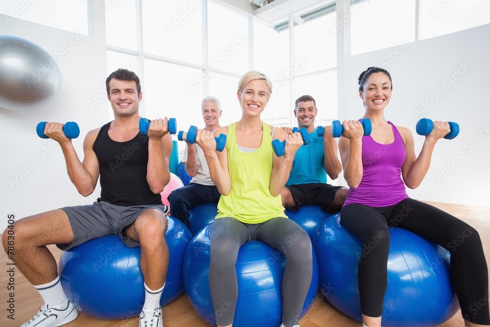 People sitting on balls and lifting weights in fitness club People sitting on balls and lifting weights in fitness club