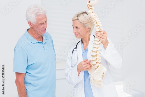 Doctor and senior patient discussing over anatomical spine