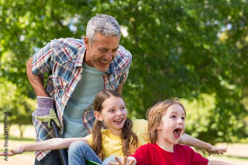 Happy father and his children playing with a wheelbarrow