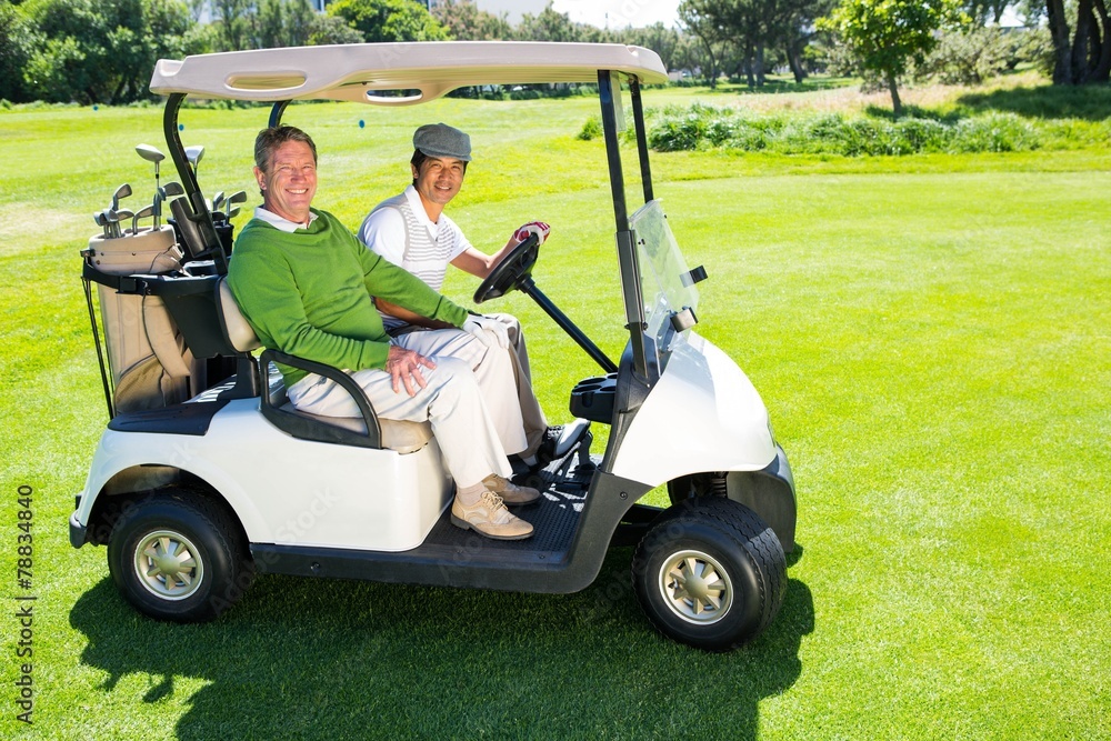 Golfing friends driving in their golf buggy smiling at camera Golfing friends driving in their golf buggy smiling at camera