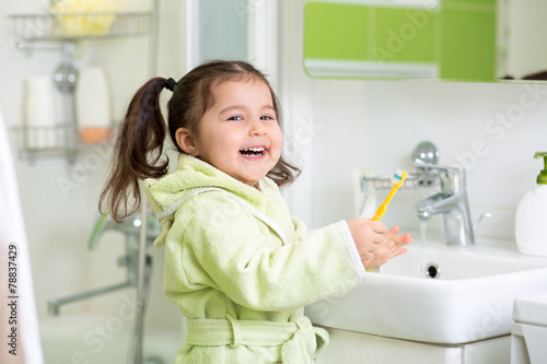 Smiling little girl brushin...