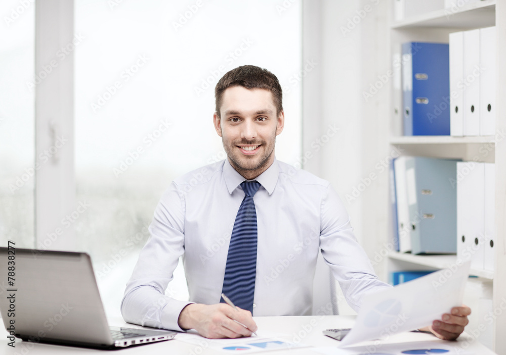 smiling businessman with laptop and documents