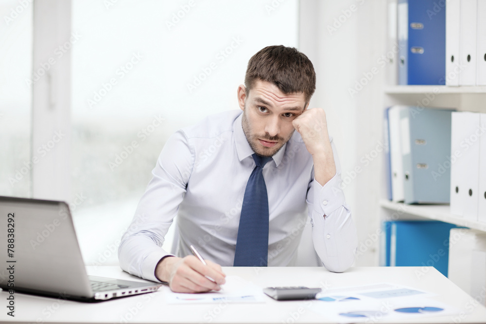 stressed businessman with laptop and documents