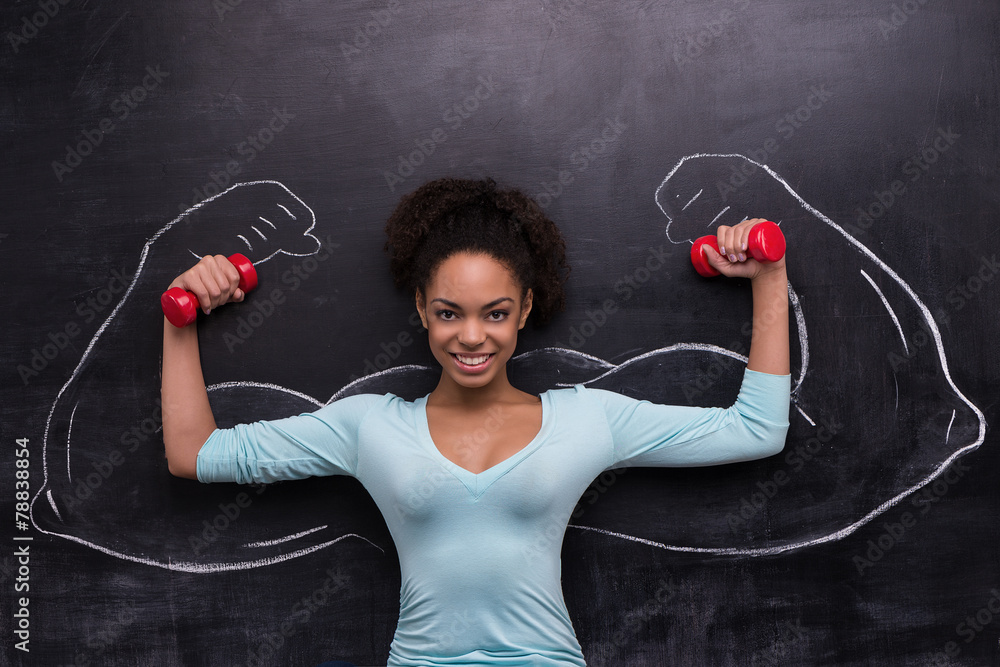Smiling afro-american woman with dumbbells and painted arms on