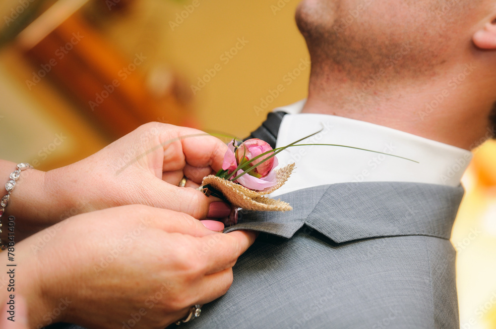 Mother putting a flower in the buttonhole of the groom dress