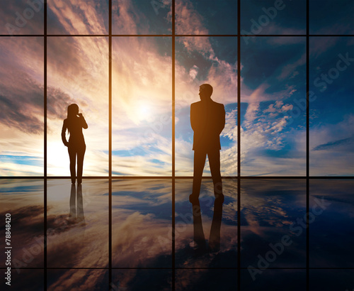 Silhouettes of businesspeople standing against panoramic window