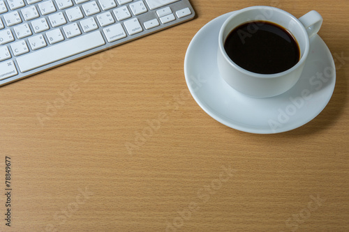 Cup of fragrant coffee on a morning paper and keyboard