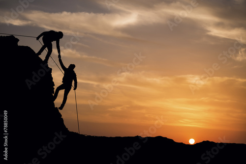 Silhouette of helping hand between two climber © sezer66