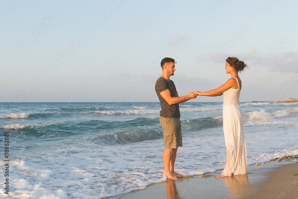 Fototapeta premium Young couple enjoys walking on a hazy beach at dusk.