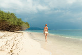 Young woman walking along tropical beach