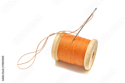 spool of orange thread and needle