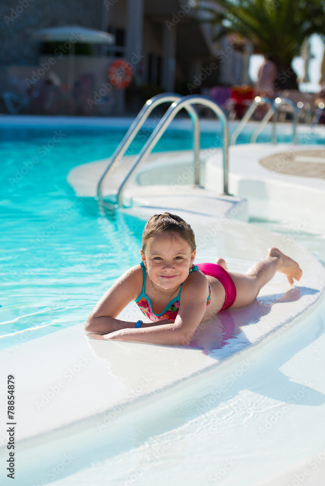 Smiling little girl relaxing in the swimming pool.