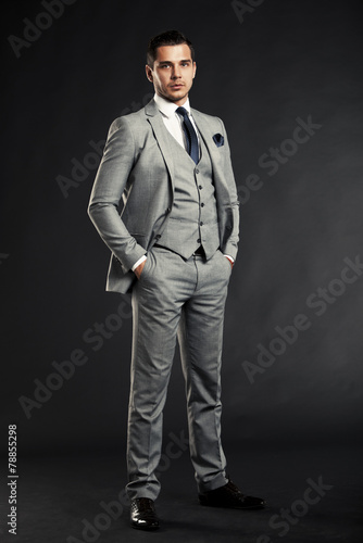 Handsome young business man standing on black background © opolja