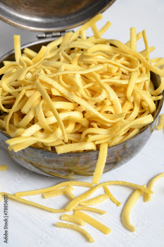 Raw, uncooked pasta in a metal pot with a lid