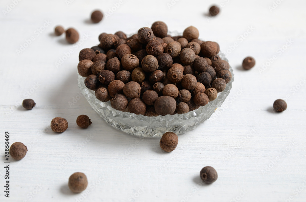 Whole allspice peppers on a white table Whole allspice peppers on a white table
