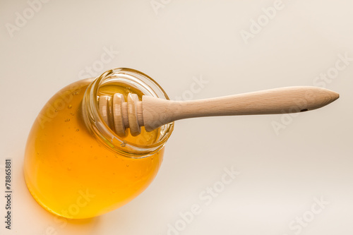 Glass jar of honey with wooden drizzler