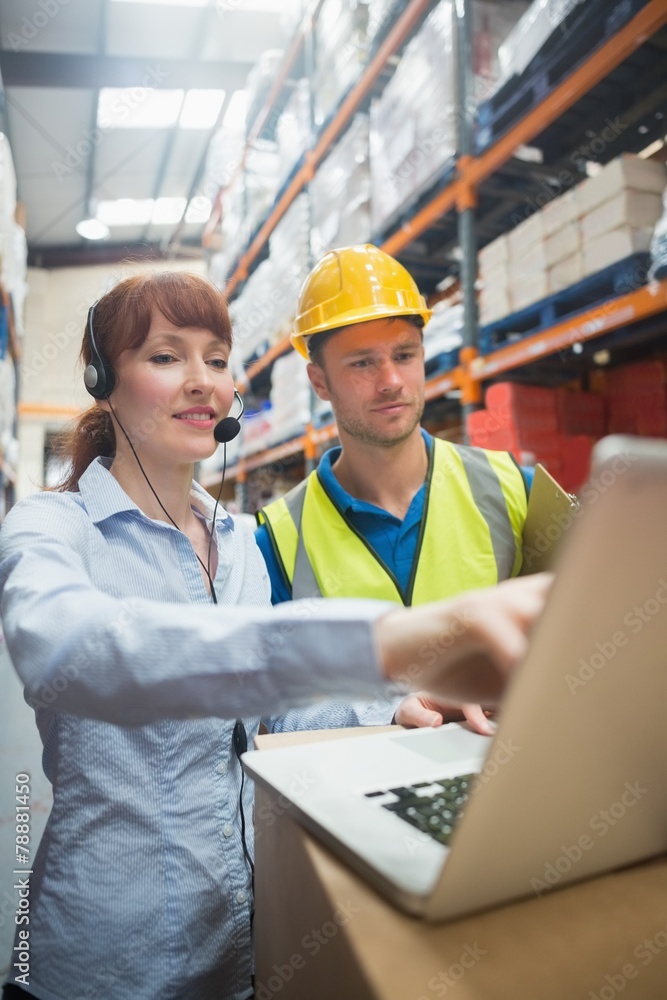 Smiling businesswoman wearing headset using laptop Smiling businesswoman wearing headset using laptop