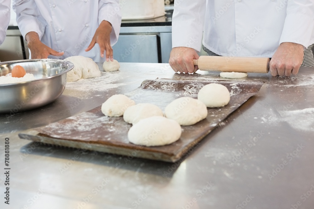 Fototapeta premium Colleagues kneading dough with rolling pin