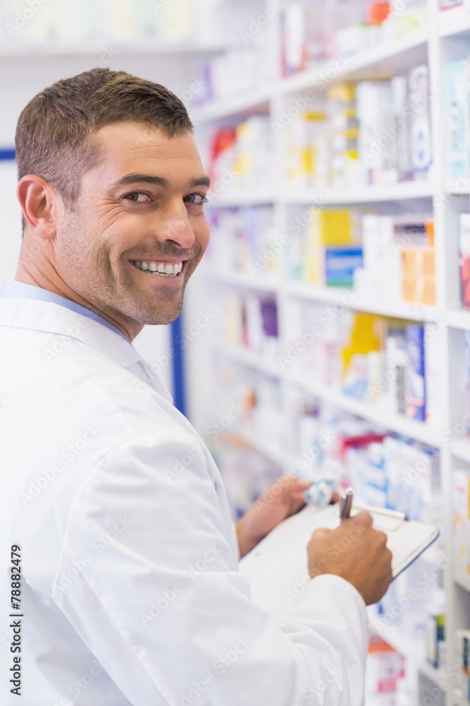 Happy pharmacist writing on clipboard