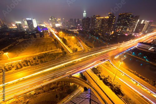 traffic light trails on overpass and cityscape at night
