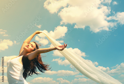 Happy young woman holding white scarf with opened arms expressin photo