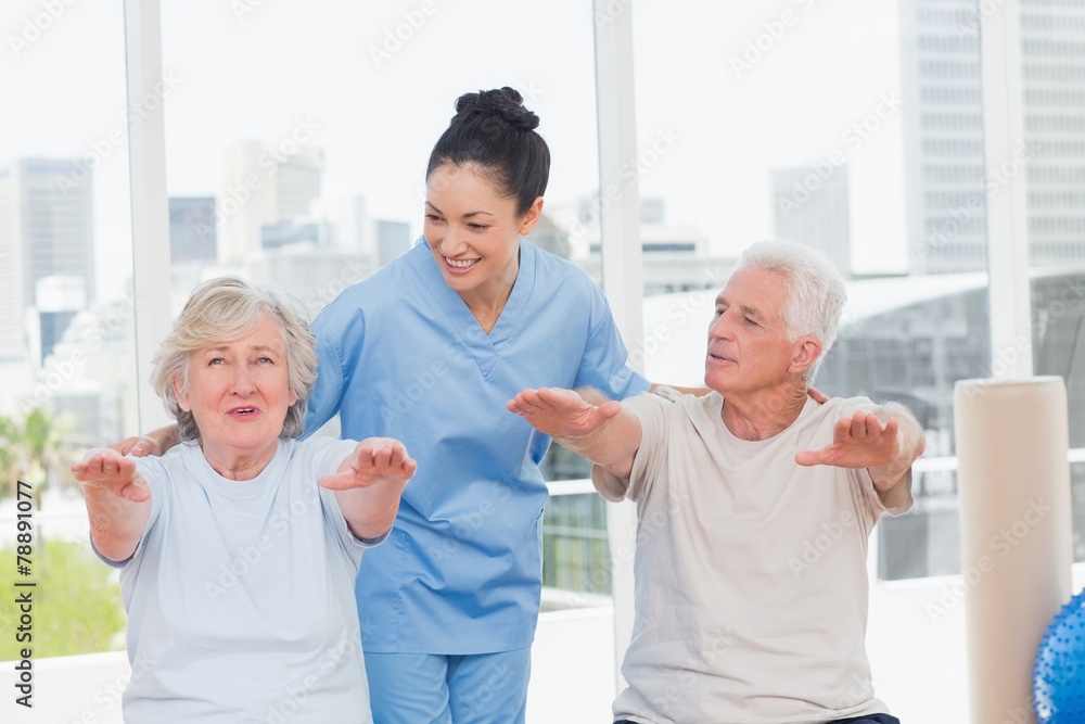 Trainer assisting senior couple to exercise Trainer assisting senior couple to exercise