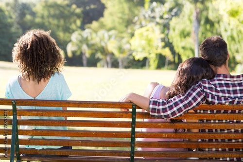 Lonely woman sitting with couple in park