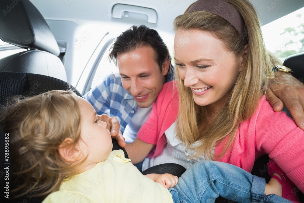 Parents securing baby in the car seat Parents securing baby in the car seat
